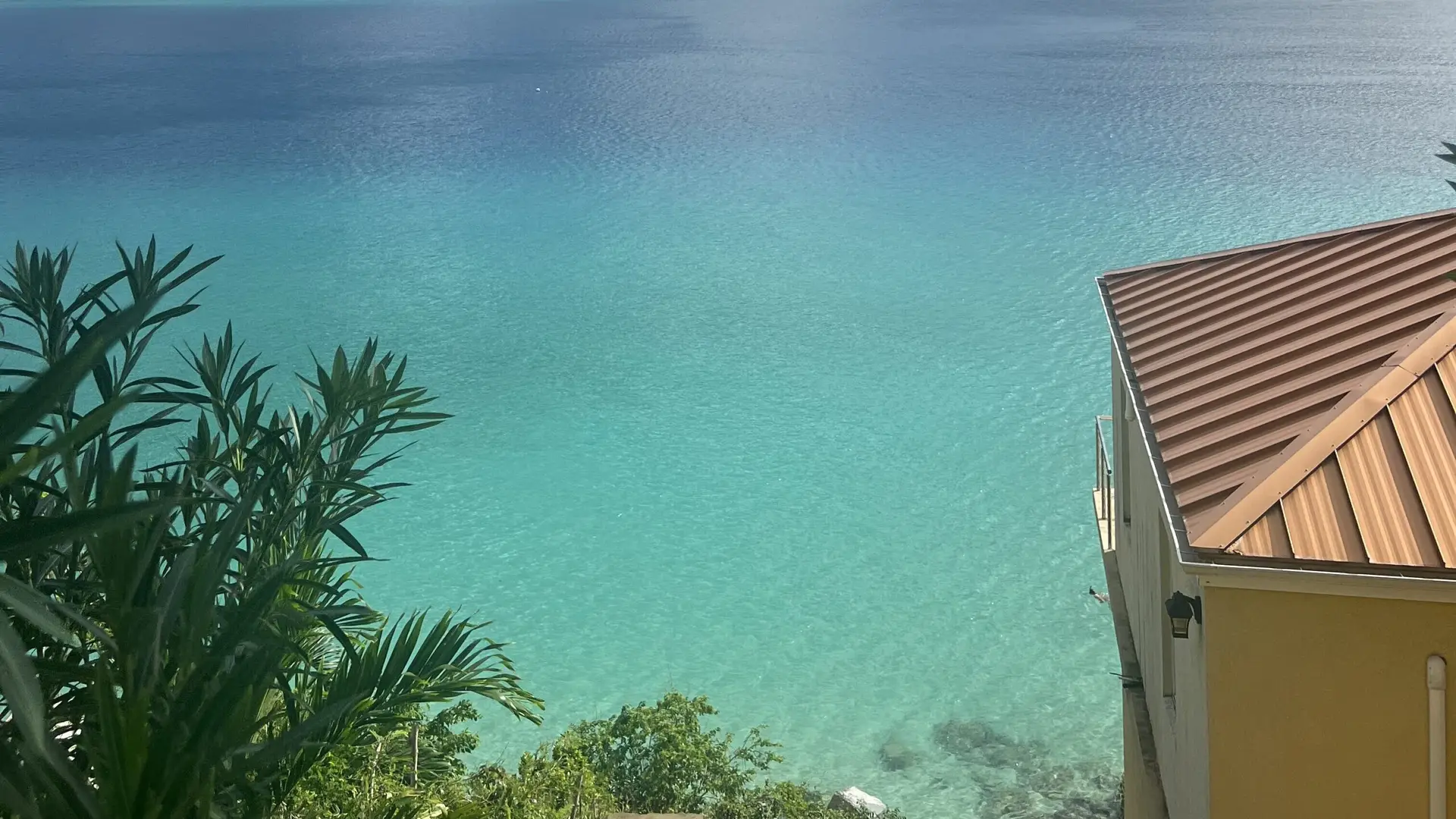 View from Sailfish Villa overlooking Magens Bay Beach, showcasing clear turquoise waters and lush surrounding scenery.